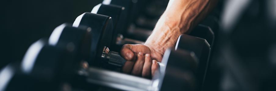 Man Lifting Commercial Dumbbell Off Rack in Gym